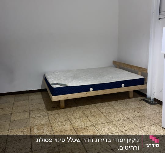 חדר עם קיר מלוכלך ומזרן על הרצפה